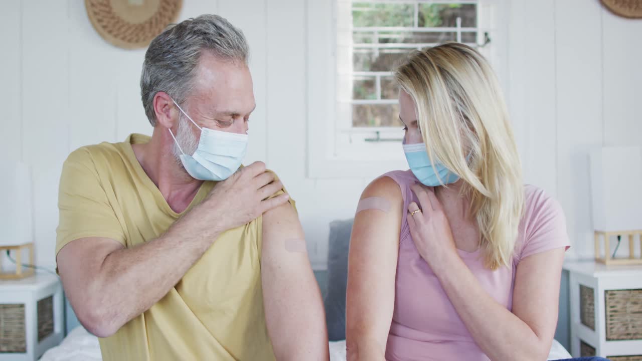 Coppia matura caucasica felice che mostra il cerotto sul braccio dopo la vaccinazione contro il coronavirus.