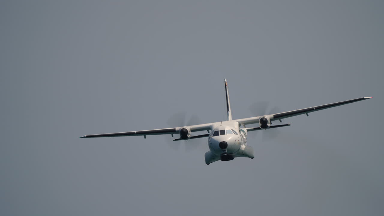 Twin propeller aircraft flying toward camera with clear view of spinning propellers