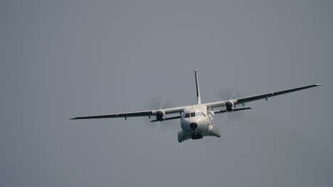 twin propeller aircraft flying toward camera with clear view of spinning propellers