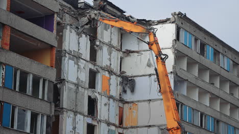 top floors destruction by the hydraulic claw of excavator. demolition of old house building for new construction by excavator bucket. view from the below.