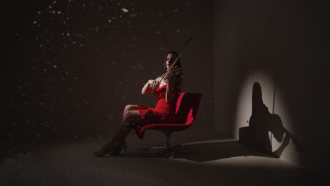 woman playing violin in a red dress with snow