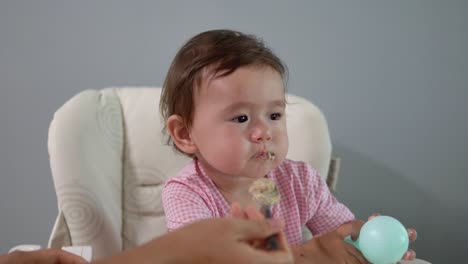 Mutter-Füttert-Babymädchen-Auf-Einem-Hochstuhl---Baby-Isst-Haferflocken