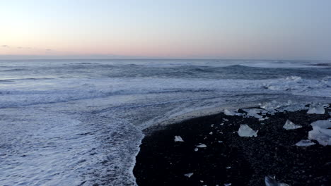AERIAL:-Flying-over-Diamond-Beach,--Black-Beach-in-Iceland-in-Winter-Snow,-Ice,-Waves,-Water