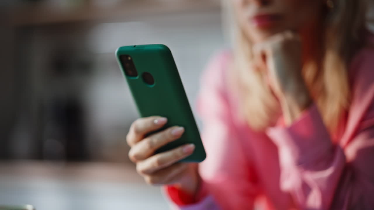 Lady hand holding cellphone reading book online at kitchen interior closeup