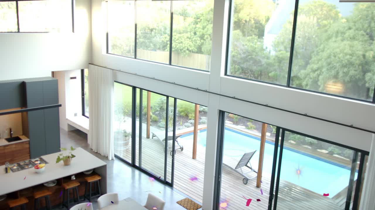 Offscreen burst sending confetti drifting and rotating across two-story kitchen, celebrating party