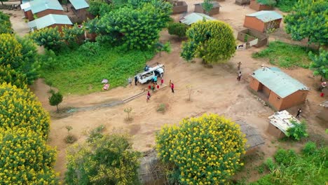 drone flying over a village with a car driving towards it