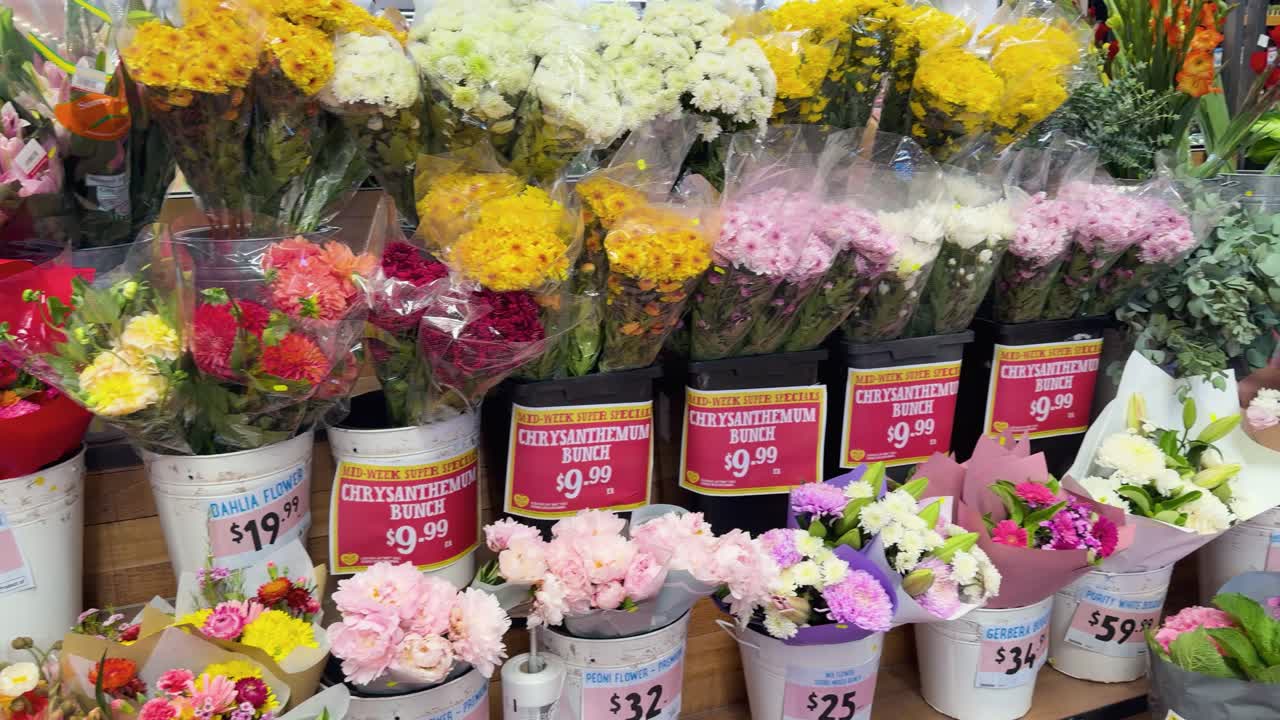 Wide shot of vibrant mixed flower bouquets in buckets, bright indoor lighting, slow camera pan