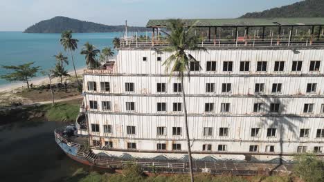 aerial view: panoramic drone view over an old land locked ship, old ship on the coastal beach with palm trees