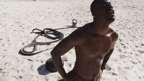 hombre afroamericano cansado tomando un descanso en el ejercicio al aire libre en la playa