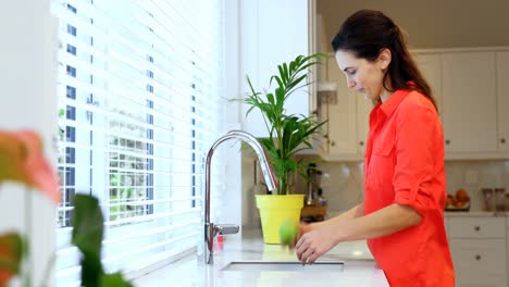 Woman-washing-apple-with-water-in-kitchen-4k