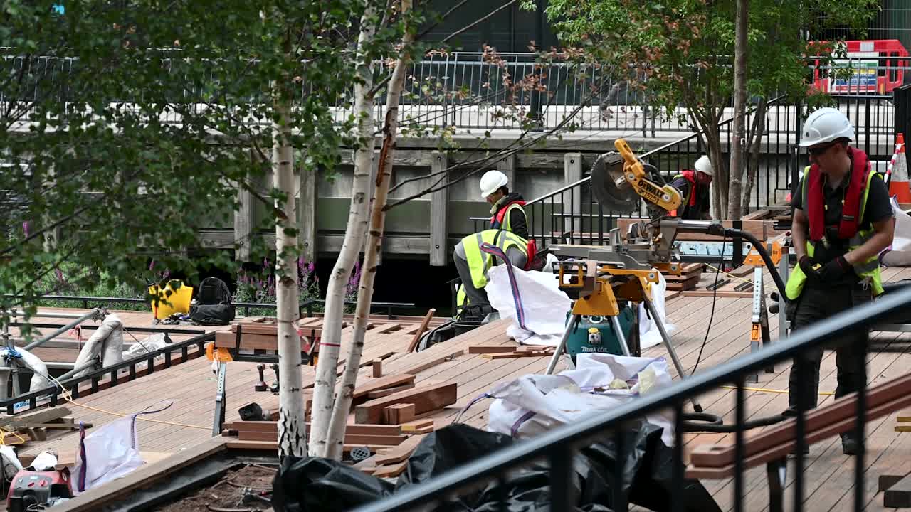 Construction workers building a wooden deck outdoors with tools and lumber