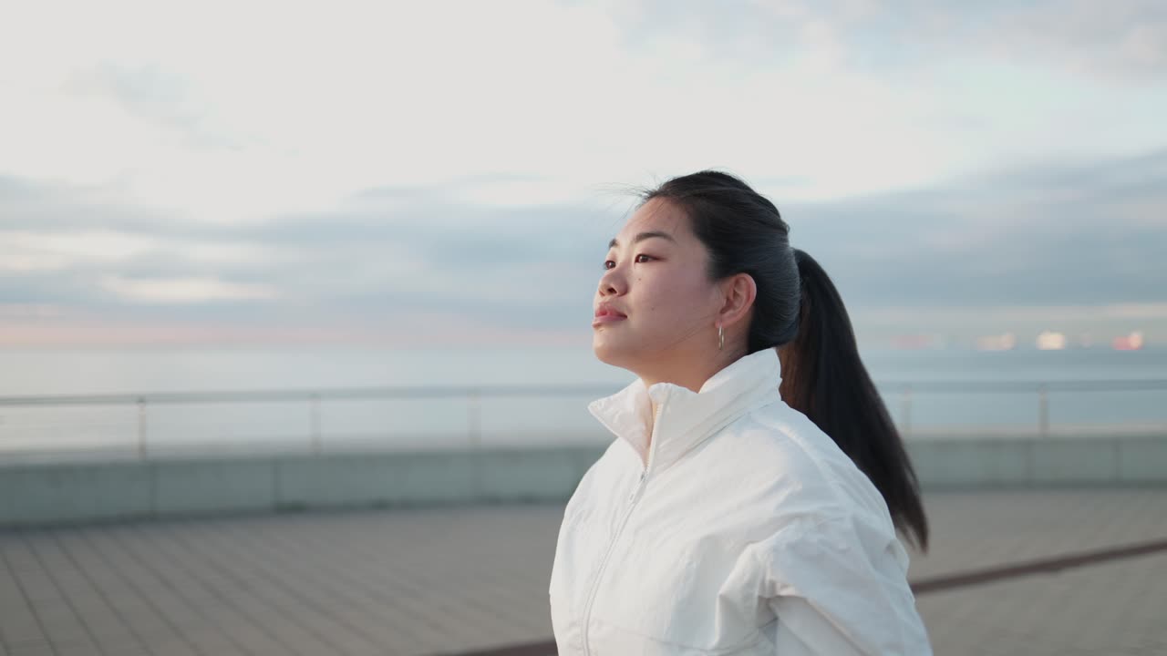 海辺の屋外で髪をポニーテールに結んでいる若いアジア人女性。