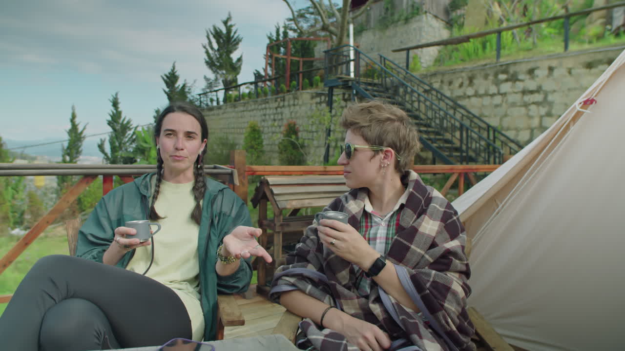 Female Tourists Resting at Glampsite in Mountains and Talking over Tea