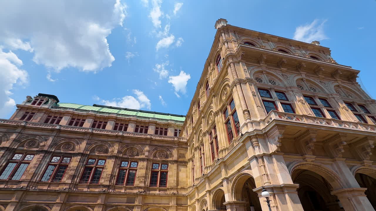 Vienna, Austria - June 9, 2025: Vienna State Opera building from low angle perspective. Façade of the stunning architecture at the backdrop of blue sky