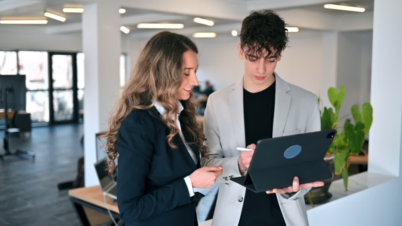 オフィスでのビジネスセッション。女性と若い男性がタブレットを使ってビジネスについて話し合っています。スローモーション。