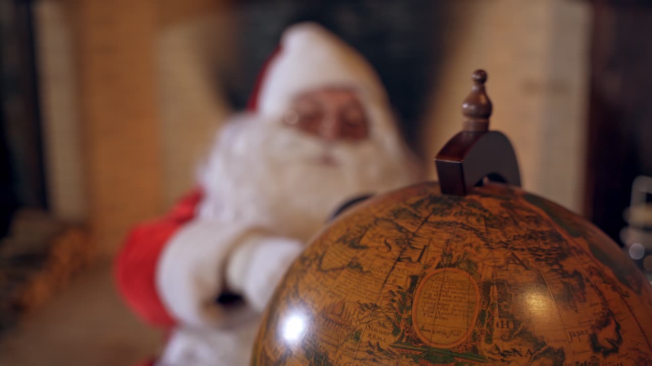 Santa Claus with globe. Big round globe and Santa looking at it through the magnifying glass. Close-up.