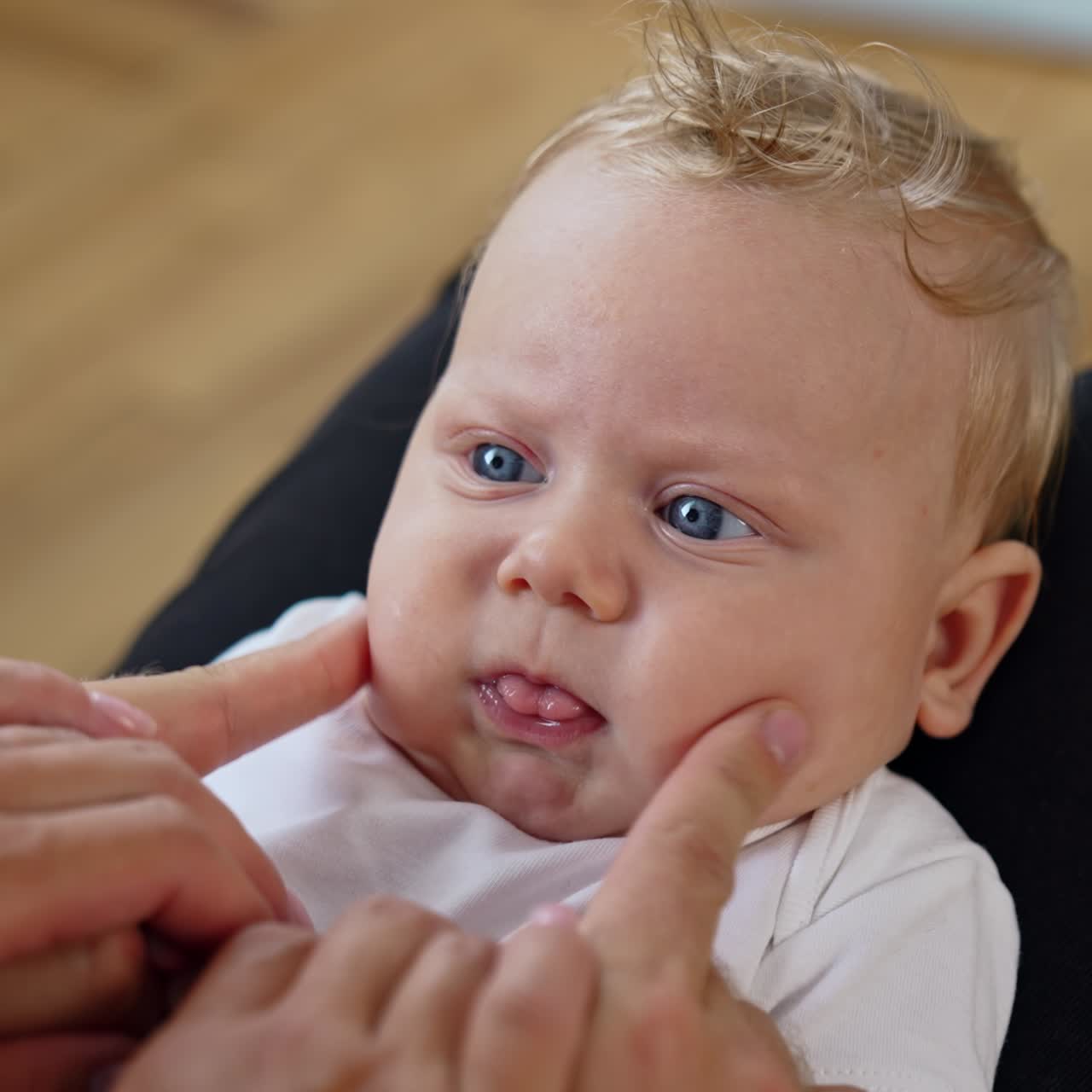 Parents play with their adorable baby. Dad's fingers touch cute plump kid's cheeks. Close up