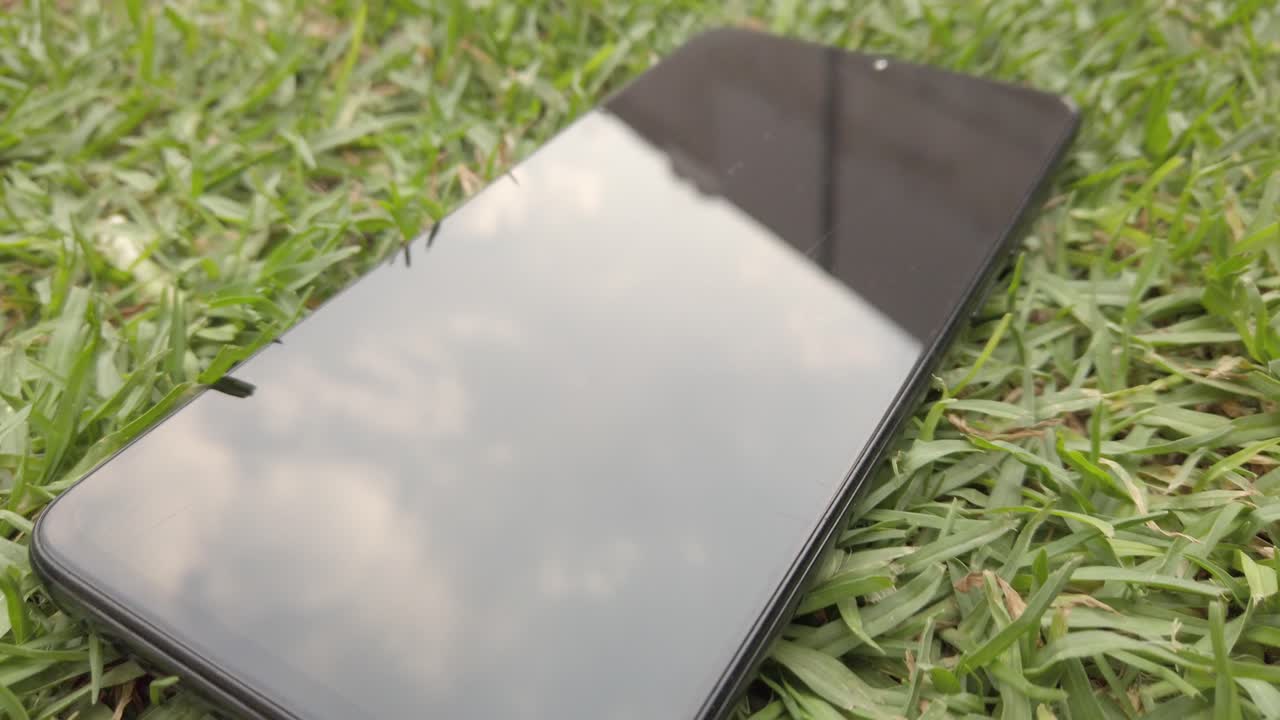 Close up shot of mobile phone on the grass, outdoor, handheld shot