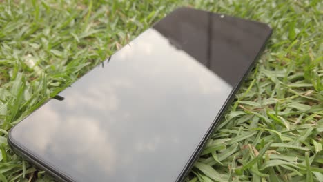 close up shot of mobile phone on the grass, outdoor, handheld shot