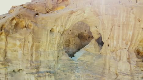 aerial close-up of a cave entrance carved into rocky cliffs.