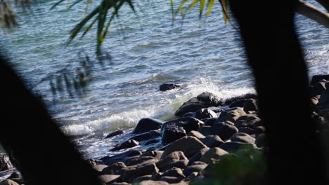 Szenische-Felsige-Strandwellen,-Die-Auf-Felsenufer-Mit-Baumvordergrund,-4k-Zeitlupe-Krachen