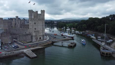 ancient caernarfon castle welsh harbour town aerial view medieval waterfront landmark right orbit slow above tourist boat