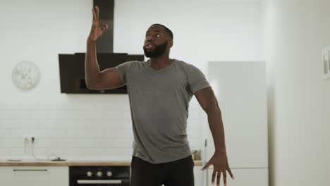 Serious-black-man-dancing-hip-hop-at-kitchen.-Young-dancer-warming-up-at-home.