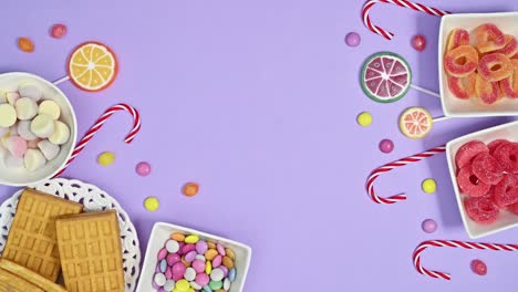 sweets, candies and lollipops arrangement appear on pastel purple background. stop motion flat lay