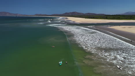 aerial view over surfers on the coastline of guanacaste, sunny day in costa rica