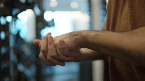 primer plano - hombre estirando la muñeca en el gimnasio, manos calentándose rutina antes del entrenamiento