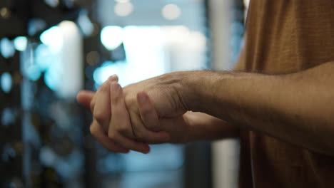 close-up - man stretching wrist in gym, hands warm up routine before workout