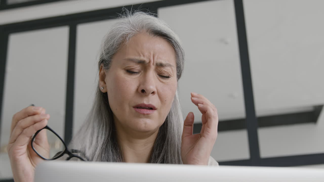 집에서 소파에 앉아 노트북 작업을 하는 동안 두통이 있는 중년 여성 2