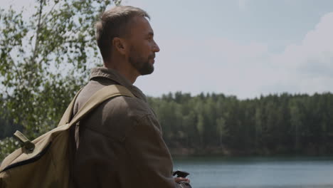 man with backpack near lake