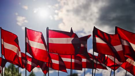 latvian flags wave in slow motion with cloudy sky backdrop on national celebration, backlit glow on windy day