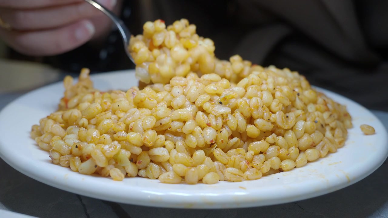 Primo piano di una persona che mangia bulgur pilaf con un cucchiaio