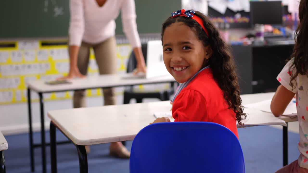 Rear view of happy Asian schoolgirl looking at camera in the classroom 4k