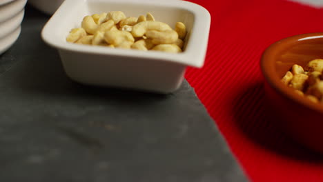 close up shot of bowls containing cashews dry roasted peanuts pistachio walnuts and hazelnut nuts revolving