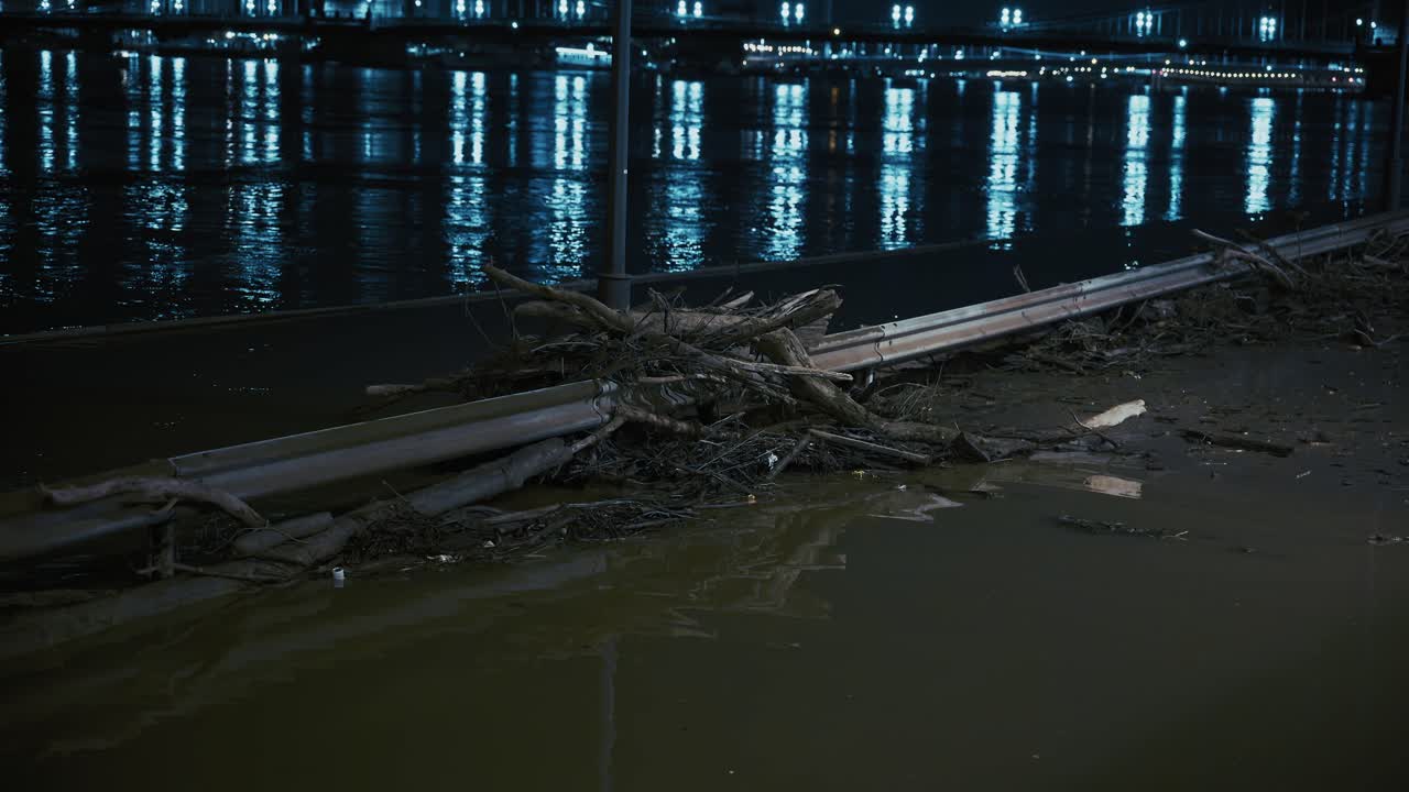 Guardrail covered with debris in Budapest riverside during nighttime flood