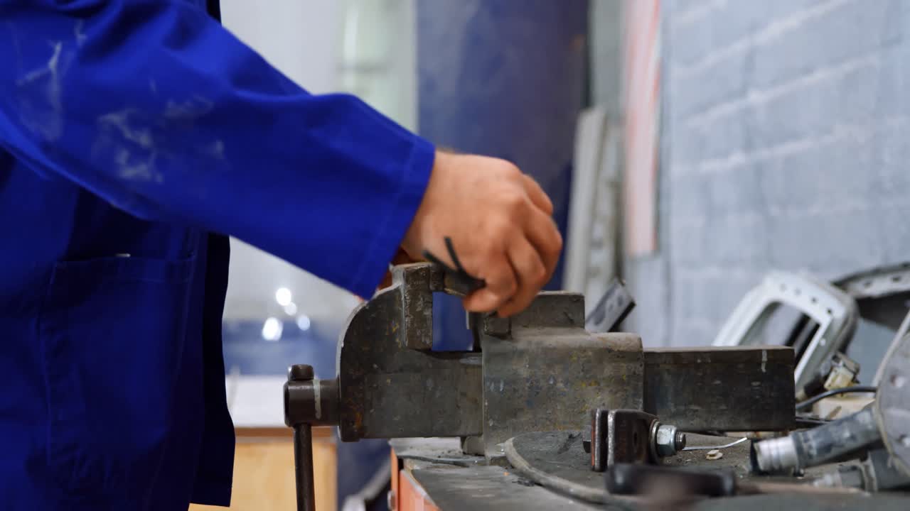 Mechanic using bench vises in garage 4k