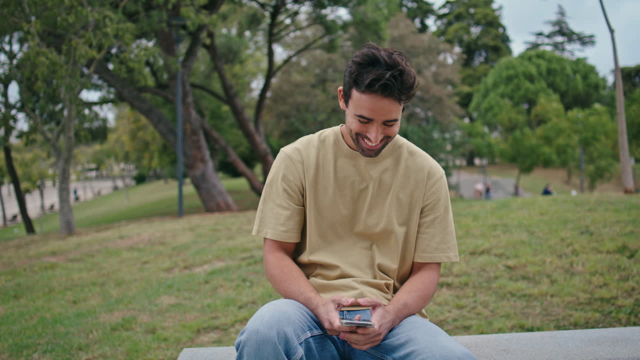 공원 벤치에서 드폰 메시지를 읽는 웃는 남자 클로즈업 행복한 히스패닉 남자