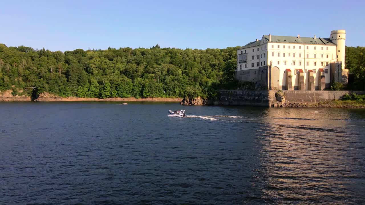 Vista panoramica del Castello di Orlik con un motoscafo sull'acqua
