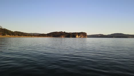 Stetige-Drohnenaufnahme-Von-Meerwasser,-Das-Bei-Sonnenaufgang-Auf-Der-Coromandel-Halbinsel-Vorbeifließt