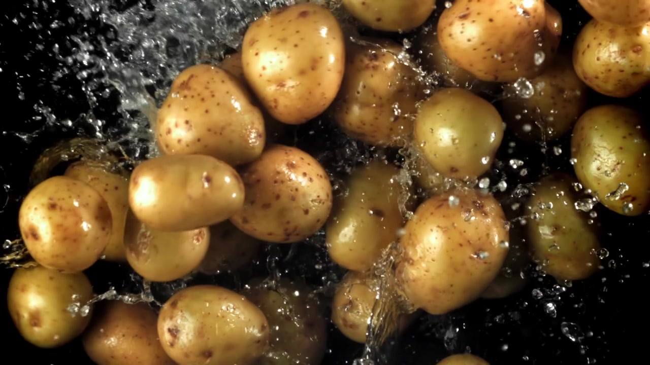 Patate fresche che cadono con schizzi d'acqua al rallentatore