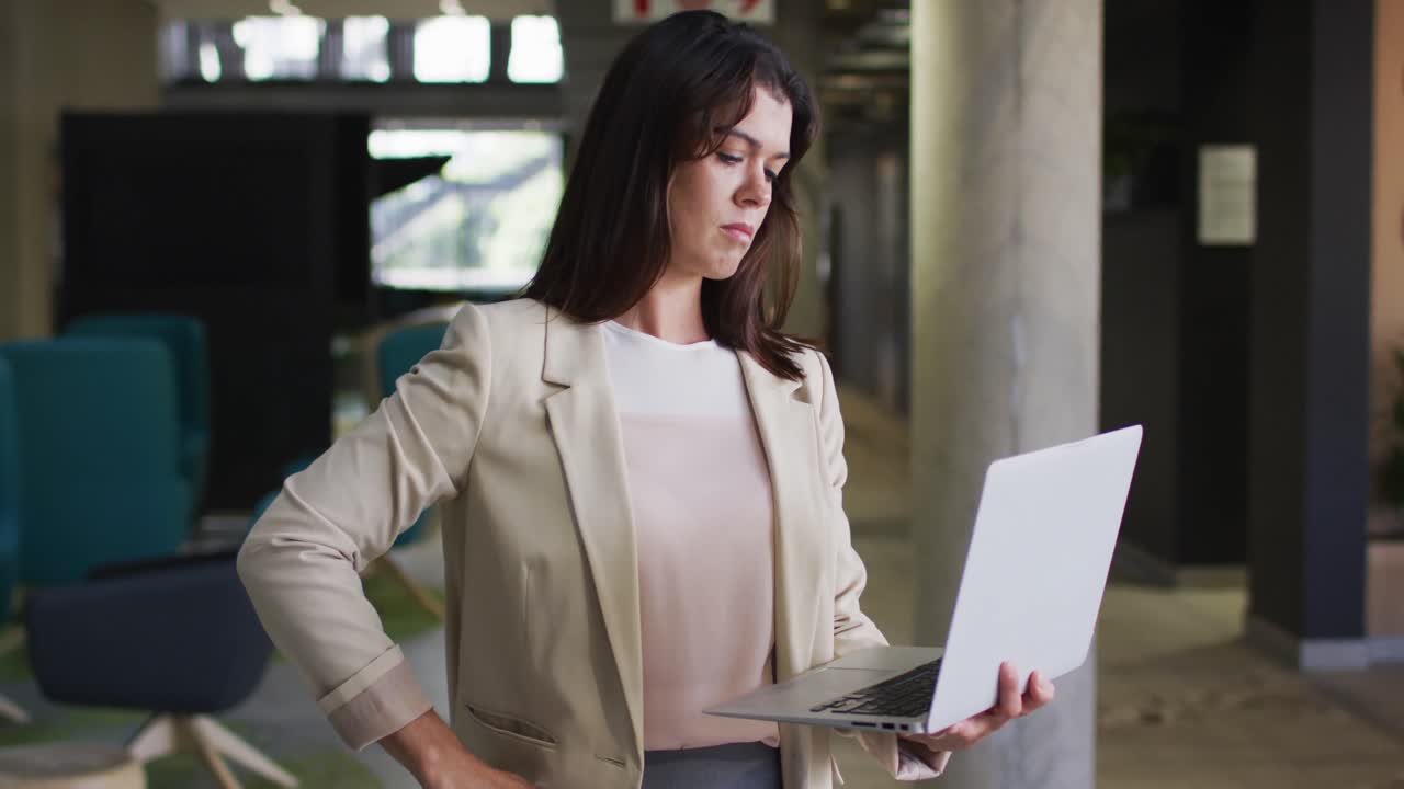 retrato de uma mulher de negócios caucasiana sorridente usando um laptop em um escritório moderno