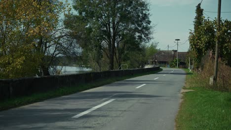 empty countryside road with trees and a stone wall by the river in lonjsko polje krapje croatia