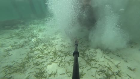 Ein-Junger,-Fitter-Und-Starker-Mann-Rennt-Schnell-Auf-Den-Holzsteg-Und-Springt-Mit-Einem-Großen-Platsch-Ins-Wasser,-Wobei-Sand-Vom-Boden-Aufsteigt