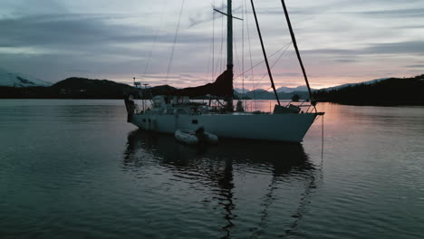 Aerial-closeup-of-a-sailing-boat-anchored-in-front-of-the-Perry-Island,-sunset-in-Alaska