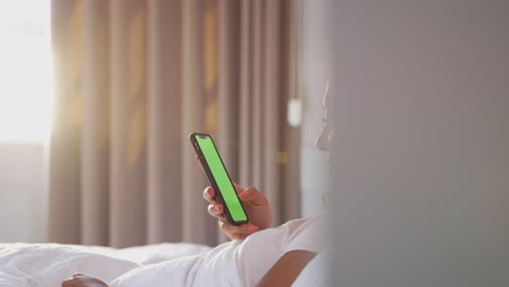 Woman-Sitting-Up-In-Bed-Looking-At-Mobile-Phone-After-Having-Woken-Up