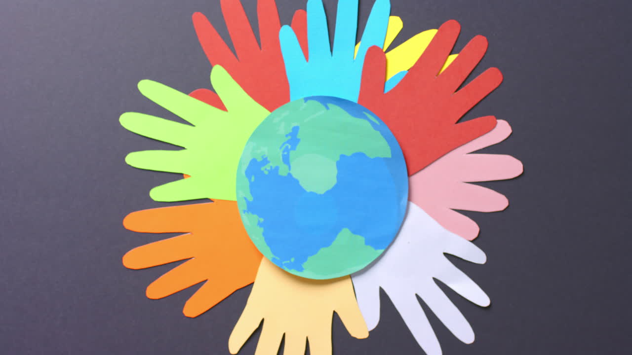 복사 공간이 있는 회색 배경에 있는 다채로운 종이로 만든 지구와 함께 손을  ⁇ 습니다.