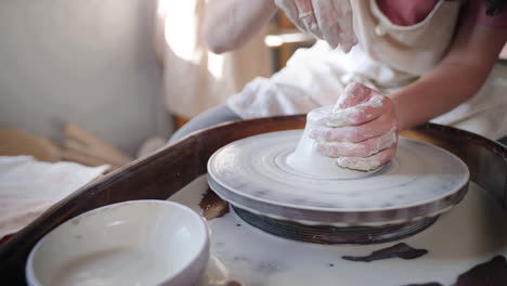 woman shaping clay on a pottery wheel